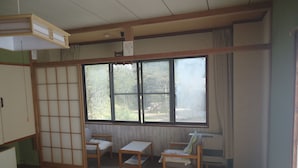 A traditional Japanese room with tatami flooring, a sliding shoji screen, and a large window with a view of the outdoors. - Le Café Cerisier (Myoko)