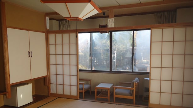 A traditional Japanese room with tatami flooring, sliding shoji doors, and a view of the outside. - Le Café Cerisier (Myoko)