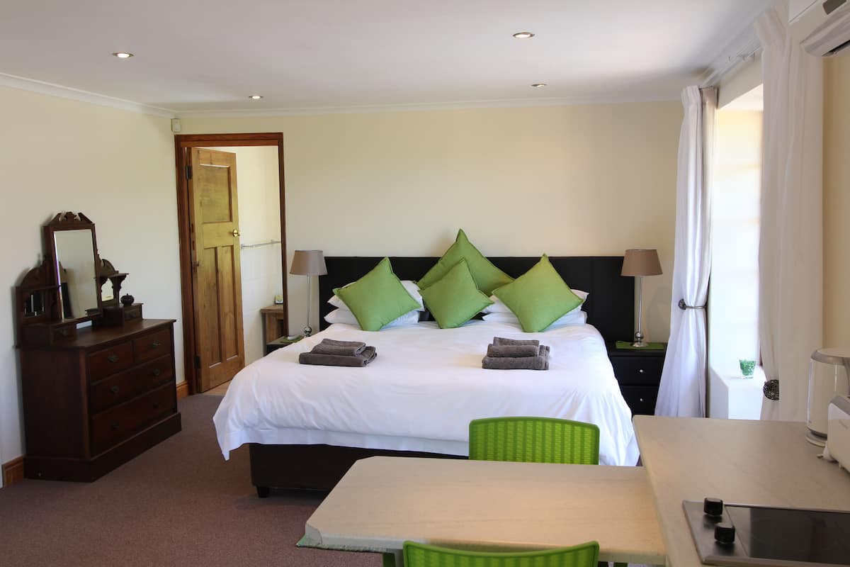 A hotel room with a bed, a dresser, a table, and a chair.