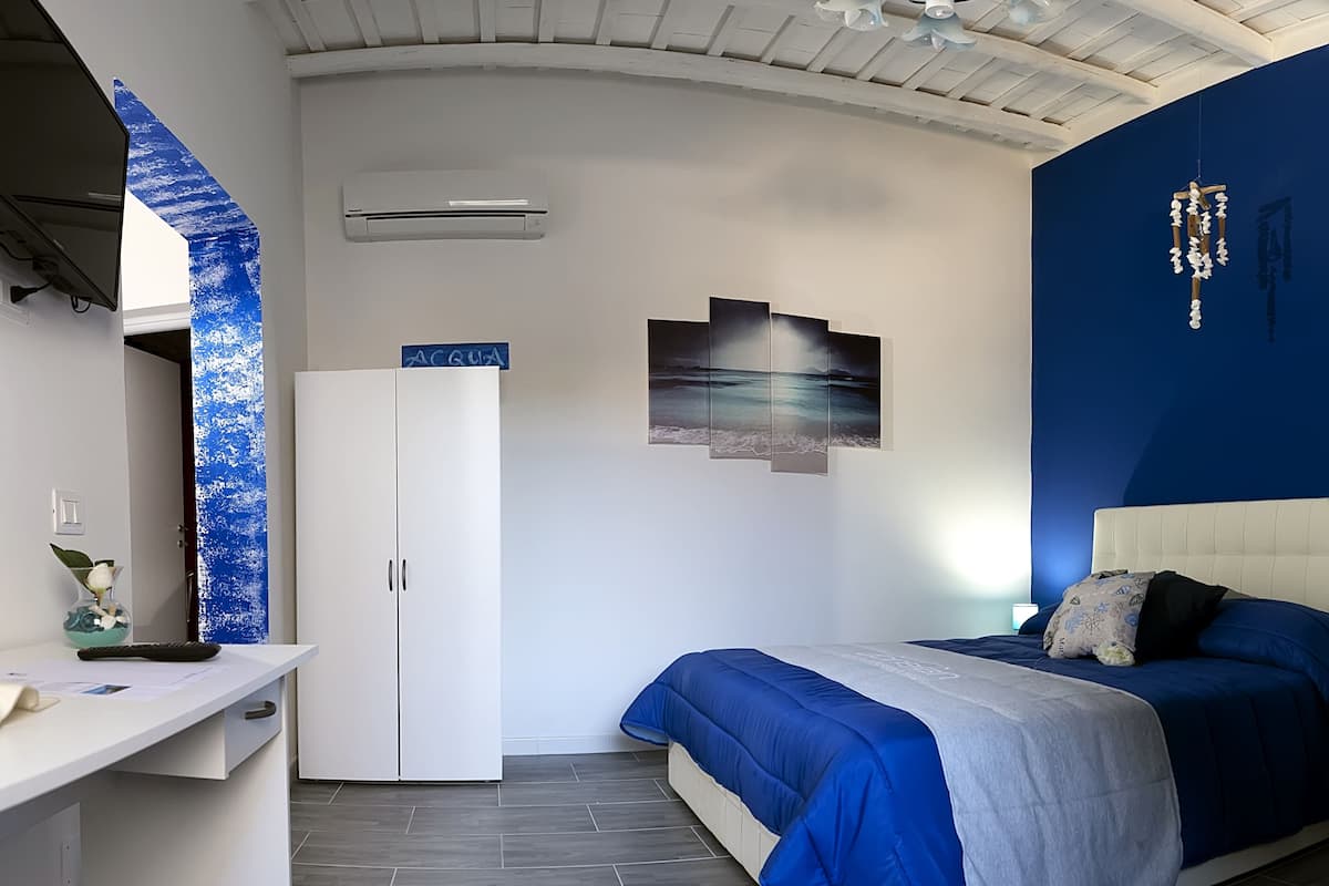 A bedroom with a bed, a desk, a wardrobe, and a ceiling fan.
