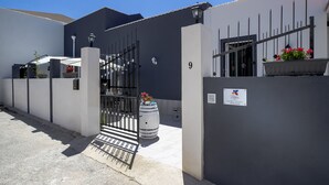 A gated residential area with a white building, a number 9 sign, and a planter with flowers. - Migair (Misiliscemi)