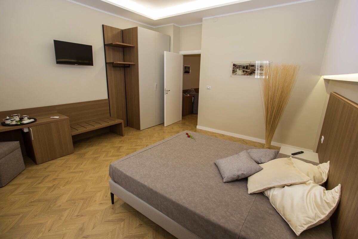 Un dormitorio pequeño con cama, mesita de noche y televisión montada en la pared.