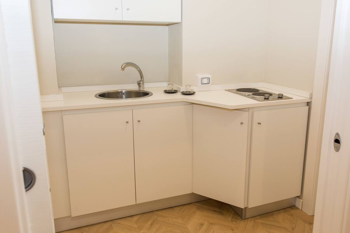 Una cocina compacta con pileta, estufa y alacenas.