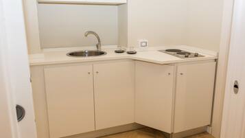 A compact kitchen with a sink, stove, and cabinets.