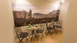 A dining area with a table set for two, chairs, and a view of a cityscape with a bridge. - Le Affacciate Bruzie Home (Cosenza)