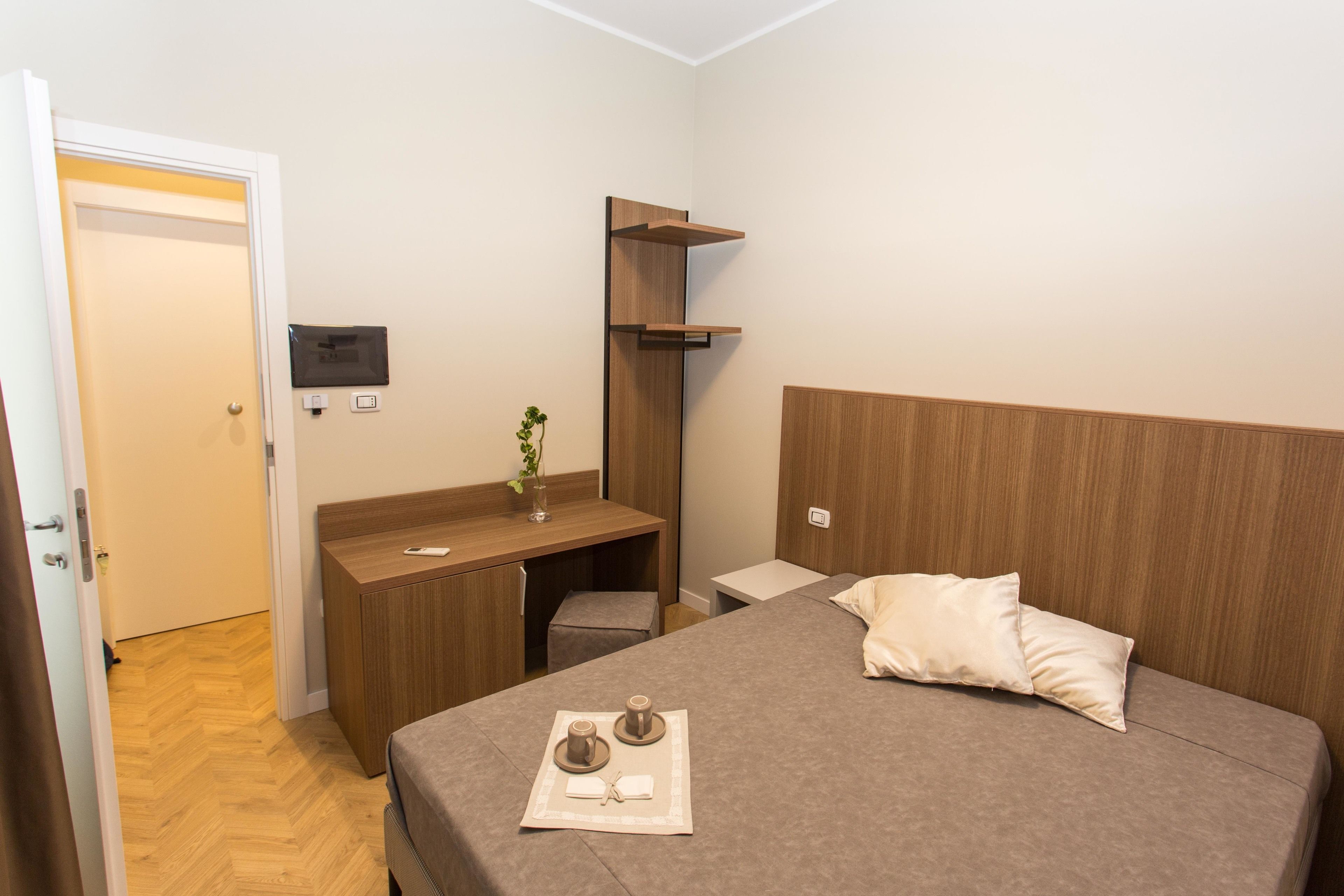 A neatly arranged bedroom with a bed, bedside table, and a desk area.