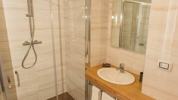 A modern bathroom with a glass-enclosed shower, a wooden vanity, and a large mirror.