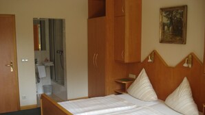 Un dormitorio con una cama de madera, una mesita de noche, un espejo y un cuadro en la pared.