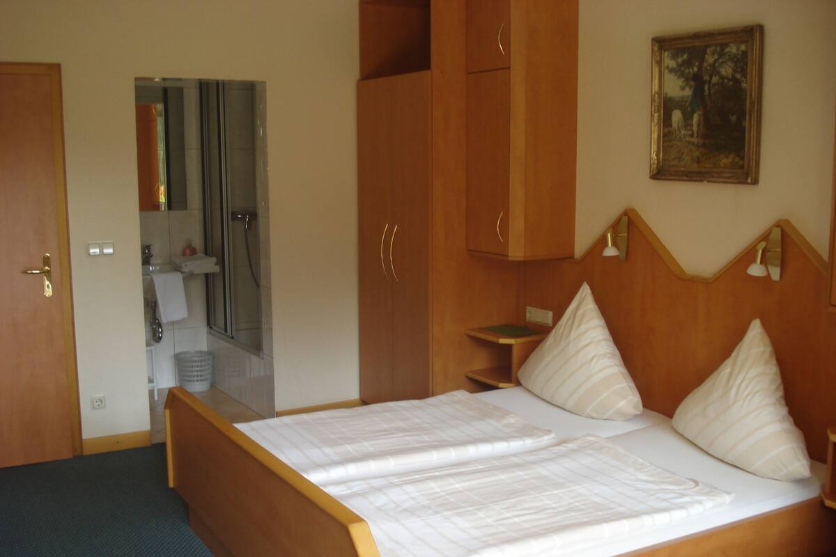 A bedroom with a wooden bed, a nightstand, a mirror, and a painting on the wall.