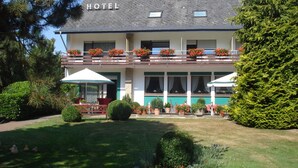 Un hotel con balcón, mobiliario exterior y un jardín bien cuidado.