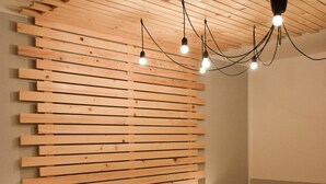 Una camera da letto con testiera in listelli di legno, un letto con copriletto dal motivo colorato, due comodini con lampade e un lampadario.