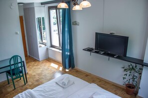 A hotel room with a bed, a desk, a chair, a television, and a window with curtains. - Park Zibert (Ljubljana)