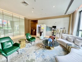Een moderne woonkamer met een leren bank in groen, een witte bank en een ronde salontafel met een blauwe vaas.