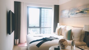 A hotel room with a bed, a round table with a book and a bottle, a globe, and a painting on the wall. - Sincere Residence Changfeng (Shanghai)