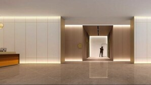 A modern hotel lobby with a reception desk, a central light feature, and a person standing in the distance. - Sincere Residence Changfeng (Shanghai)