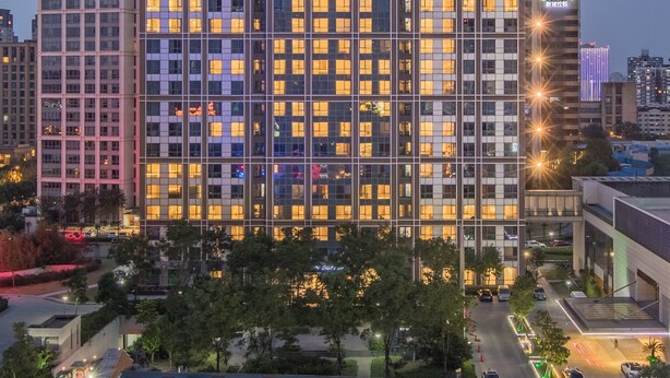 A high-rise hotel with a grid of windows, illuminated signage, and a surrounding urban environment. - Sincere Residence Changfeng (Shanghai)