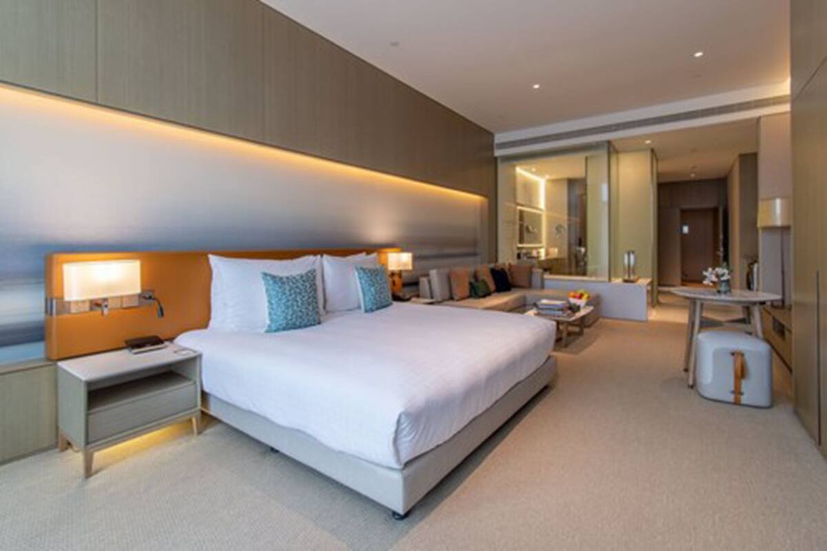 A modern hotel room with a large bed, bedside tables, a desk, and a seating area.