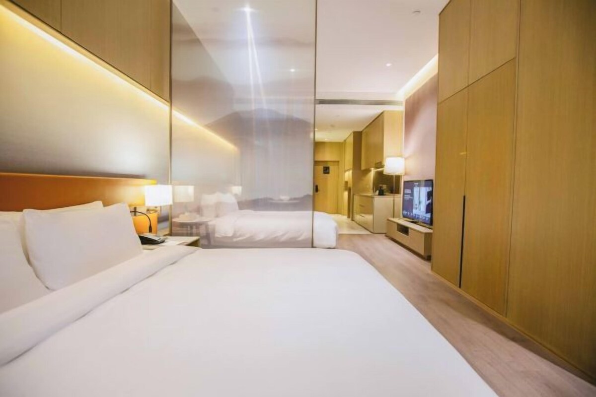 Una habitación de hotel con una cama grande, mesitas de noche, un televisor y un armario.