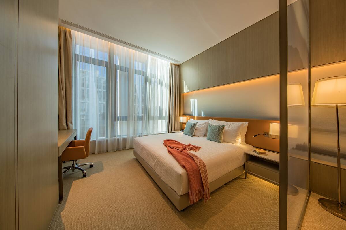 A hotel room with a large bed, a desk, and a chair.