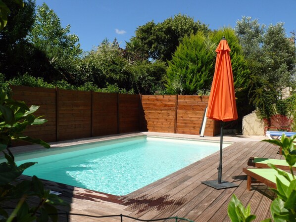 A wooden deck with a pool, surrounded by a wooden fence and lush greenery. - Les Chambres d'hôtes Clos Semper Felix (Sainte-Bazeille)