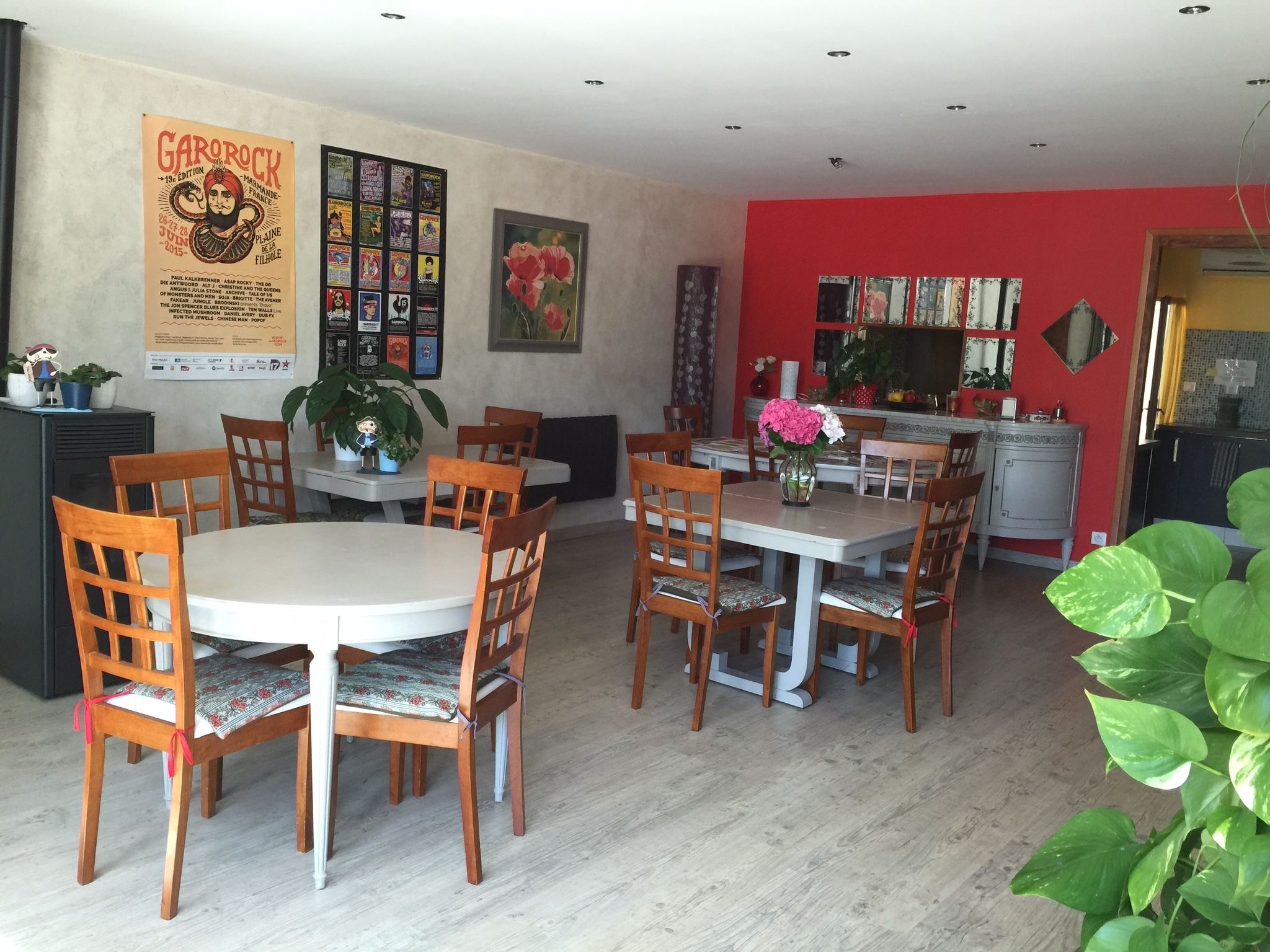 Un comedor con sillas y mesas de madera, un cartel en la pared y una pared de acento roja.