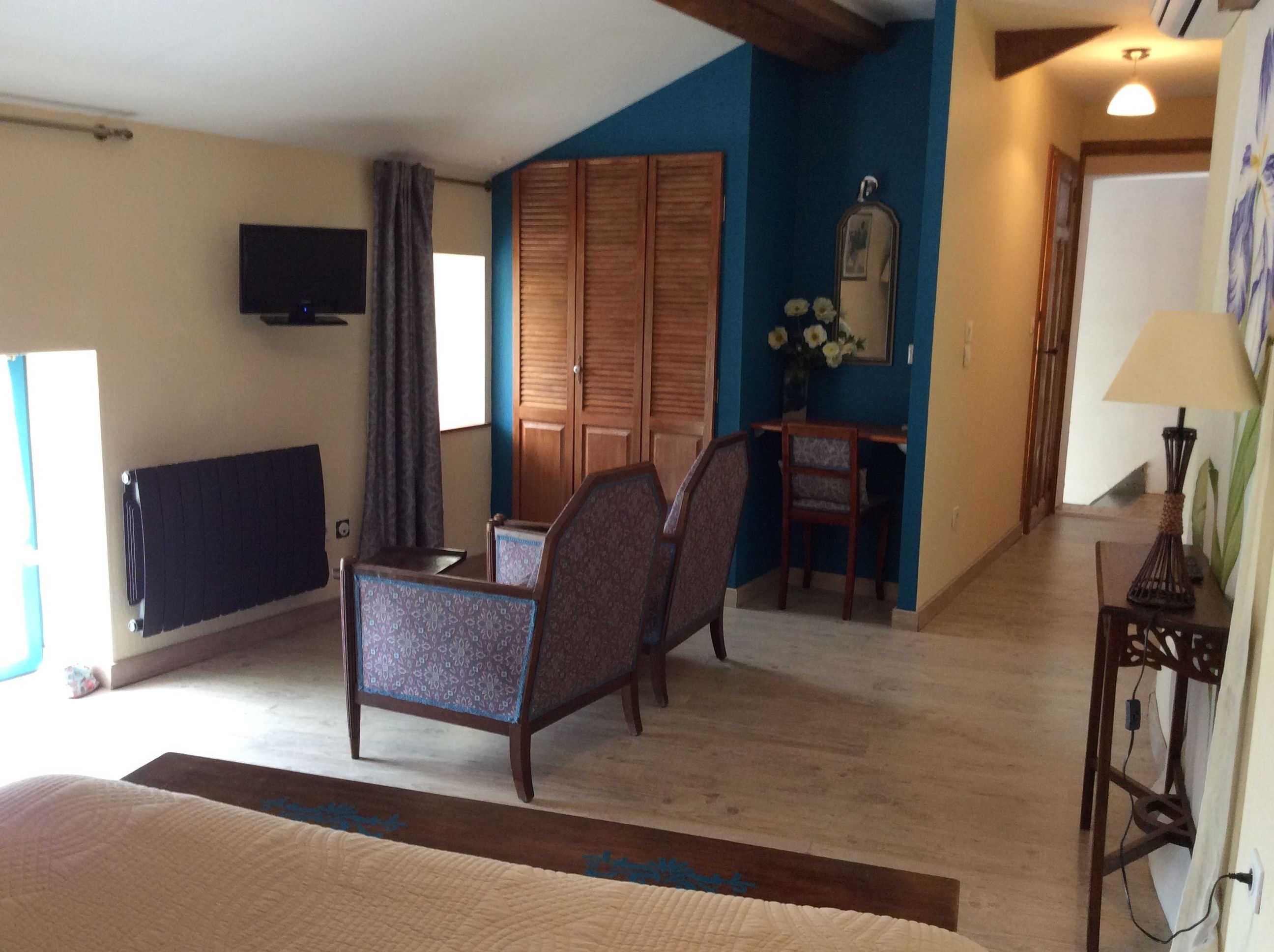 A room with a bed, a desk, a chair, a television, and a wardrobe.