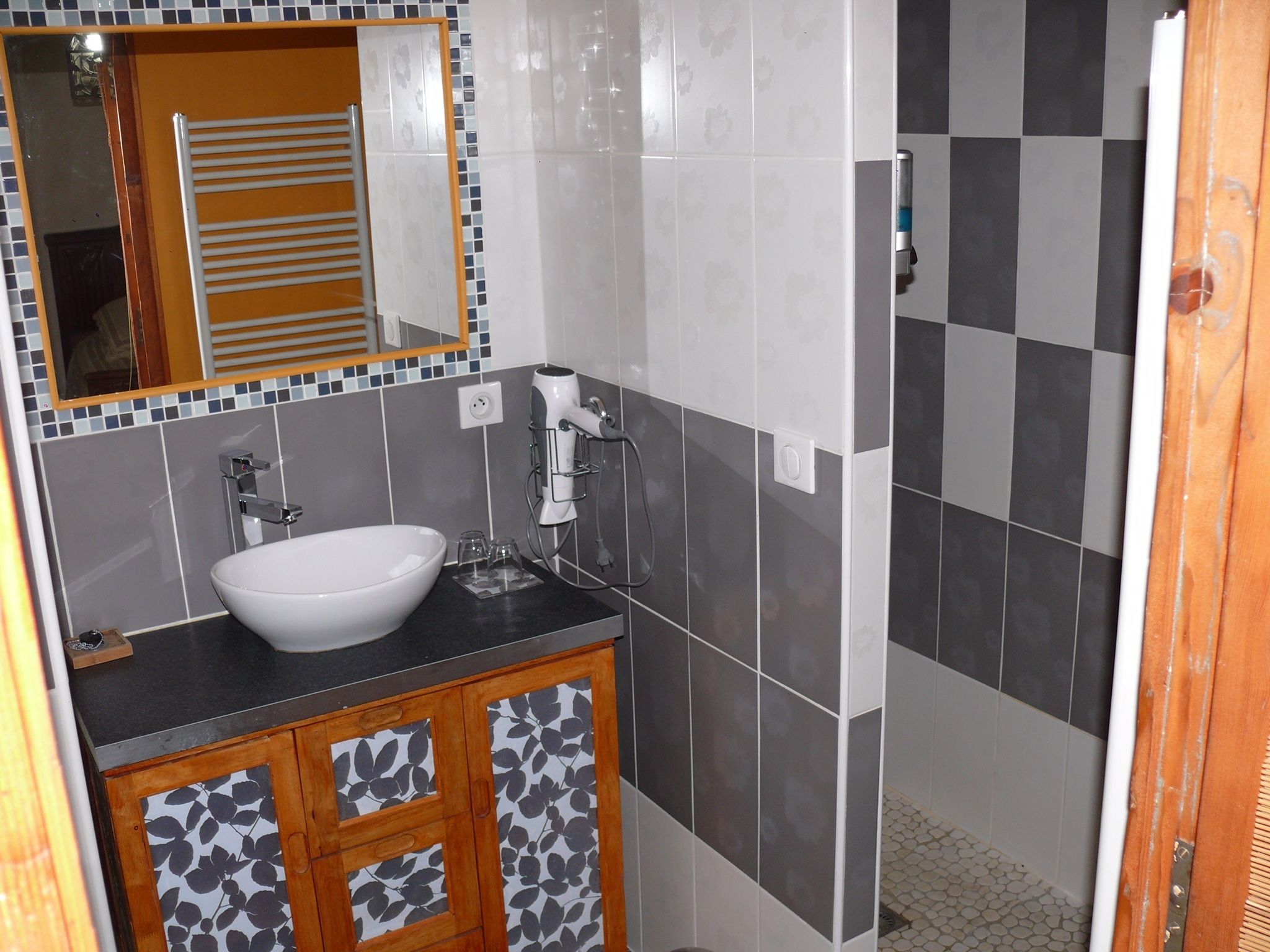 A bathroom with a white sink, a mirror, and a shower area.