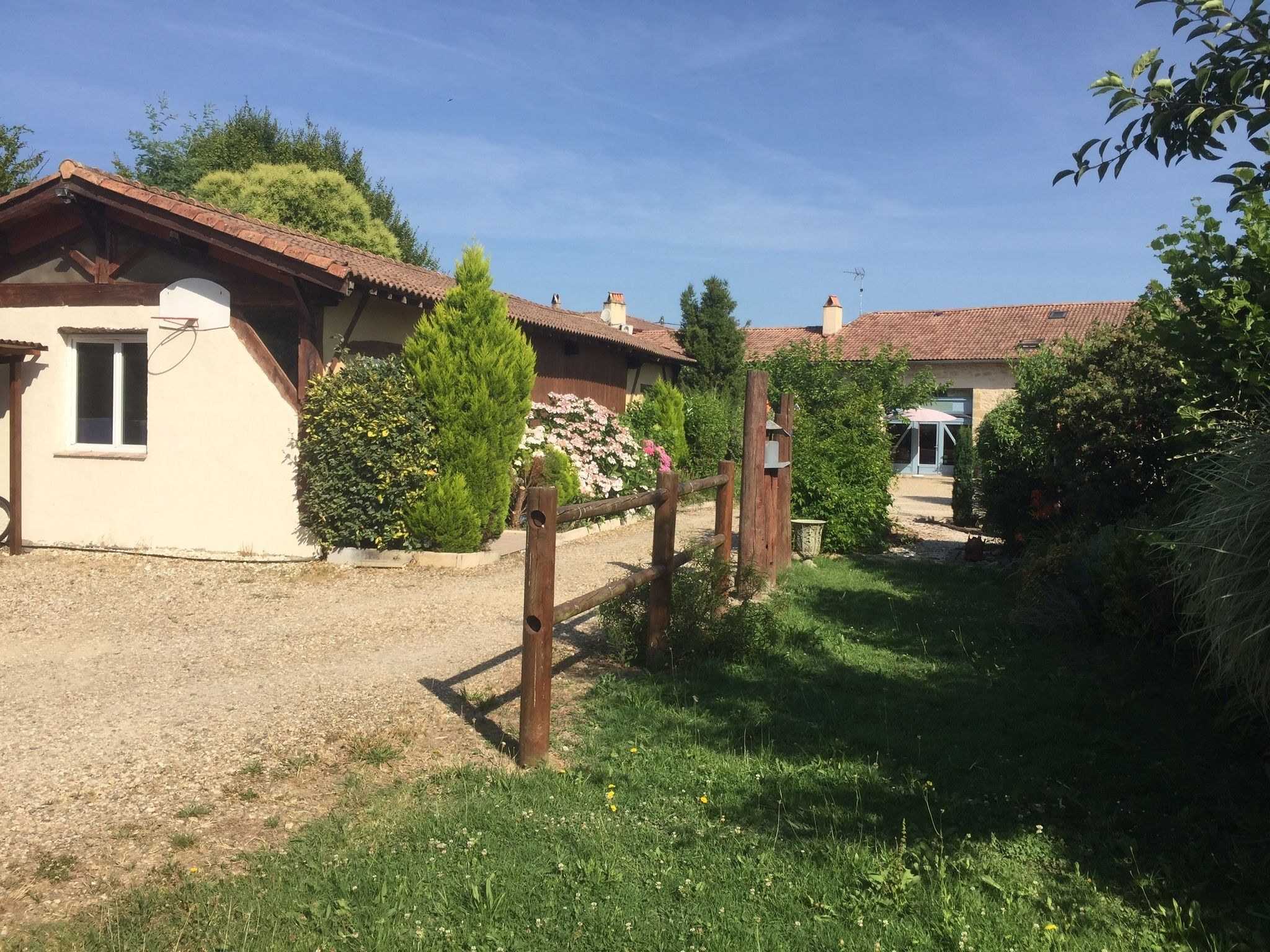 Ein ländliches Haus mit Kiesauffahrt, umgeben von Grünflächen und Bäumen.