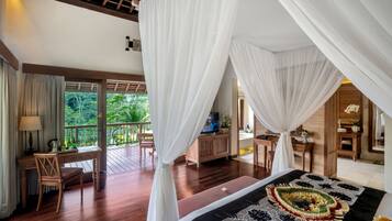 A bedroom with a bed, a desk, and a chair. There is a balcony with a view of greenery.