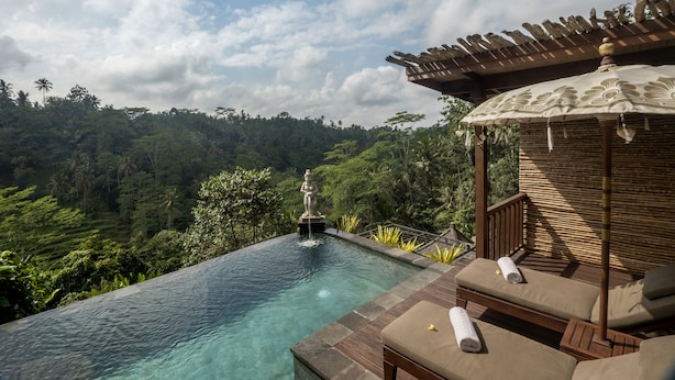 An infinity pool with a statue, wooden deck, and lounge chairs. - The Kayon Jungle Resort (Payangan)