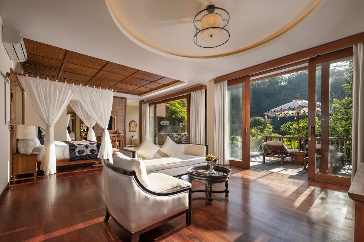 Una habitación amplia con una cama grande, un sofá y un balcón con mobiliario exterior.