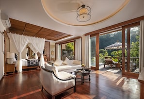 Relax in a spacious room with a comfortable seating area, sofa, and armchairs, plus a bed with a canopy.