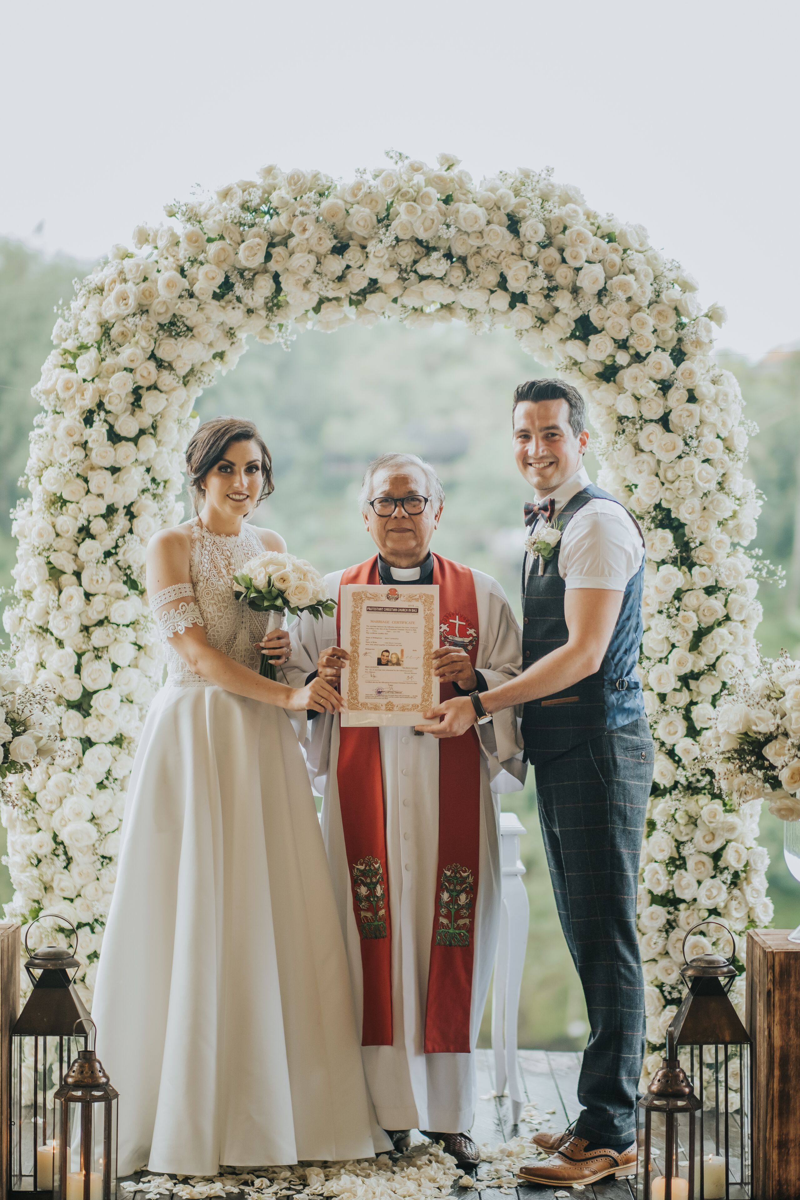 A wedding ceremony with a floral arch backdrop.