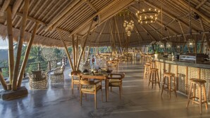 An open-air restaurant with bamboo structures, wooden furniture, and a bar area. - The Kayon Jungle Resort (Payangan)