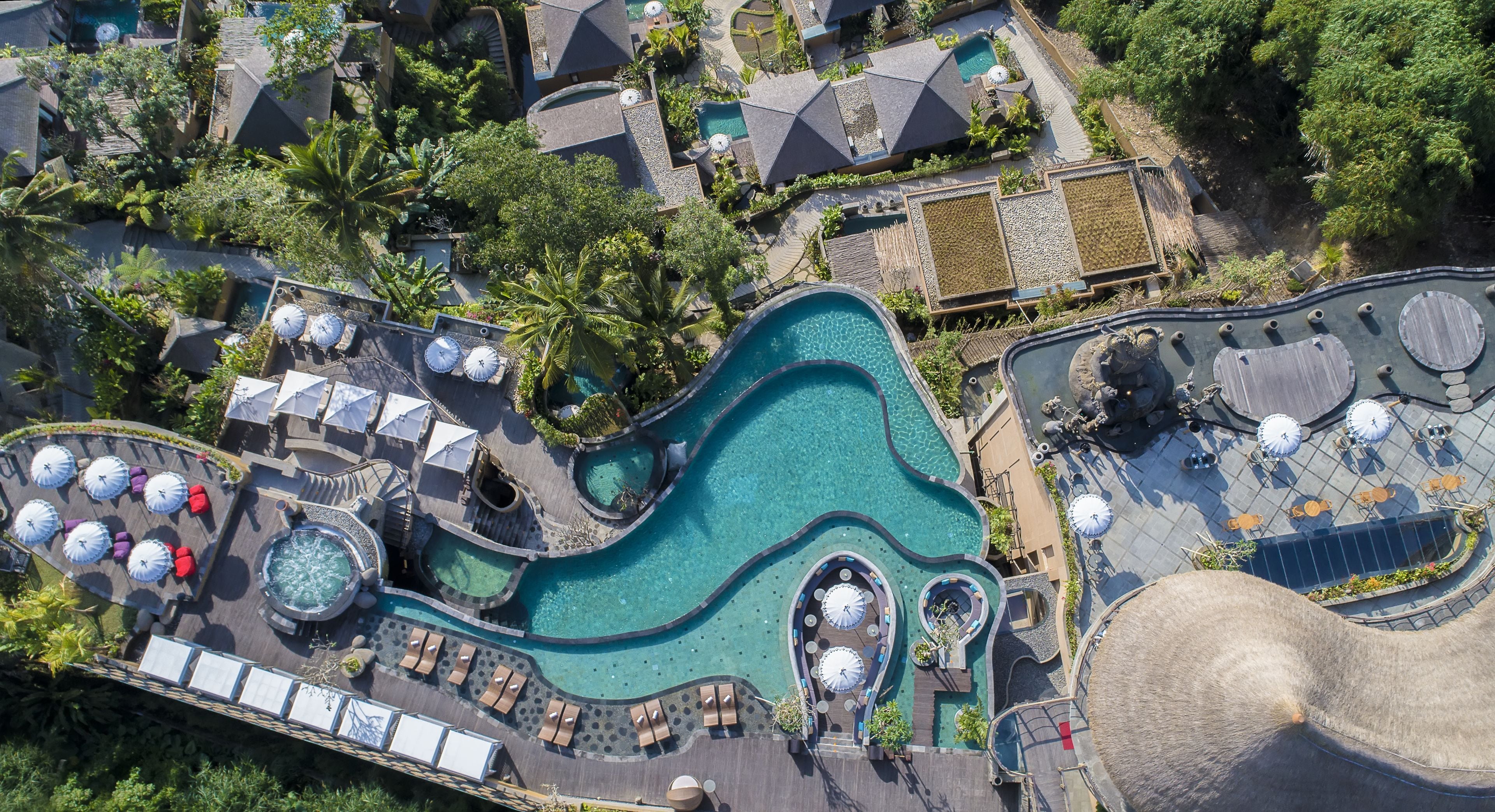 Vue aérienne d’un complexe hôtelier doté de plusieurs piscines, de chaises longues et de parasols.