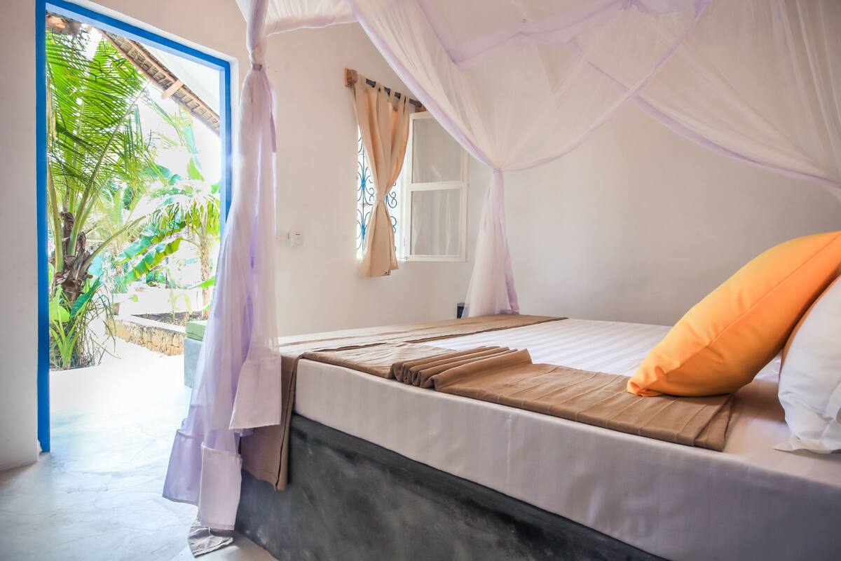 Un dormitorio con cama, ventana y vista a zonas verdes.