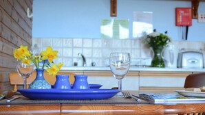 Une table à manger avec une assiette bleue, deux vases ornés de fleurs jaunes et un verre à vin.