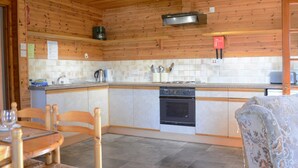 Une cuisine avec des murs en bois, un pare-feu en carrelage, une cuisinière et un lave-vaisselle.