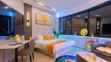 A modern hotel room with a bed, desk, and seating area.