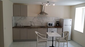 A compact kitchen with a sink, microwave, coffee maker, and dishwasher. There are two chairs and a table in the dining area. - Hotel Marcellin (Beaulieu-sur-Mer)