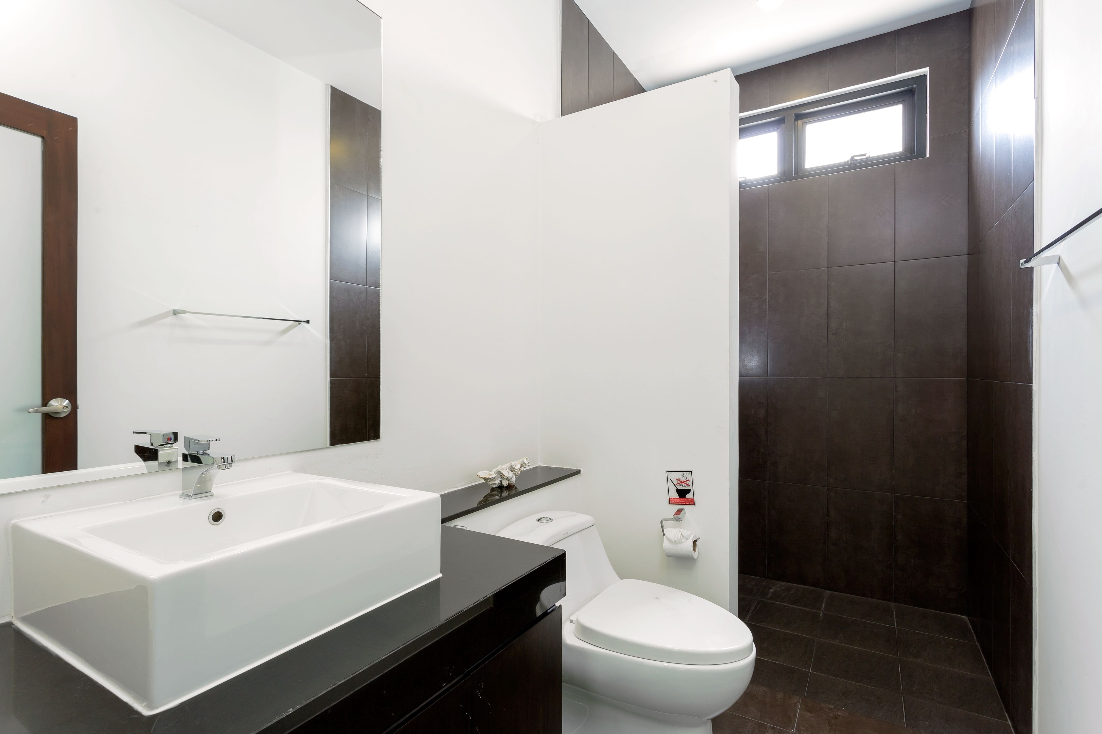 A modern bathroom with a large white sink, a toilet, and a shower area.
