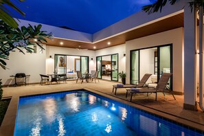 A modern outdoor pool area with lounge chairs, a dining table, and a grill. - Big Buddha View 3br Pool Villa by Intira (Rawai)