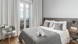 Een moderne hotelkamer met een groot bed, een fauteuil, een bijzettafeltje en uitzicht op het omliggende landschap.
