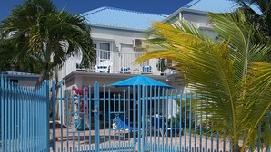 Un'area recintata con una staccionata blu, una palma e un edificio con tetto blu sullo sfondo.