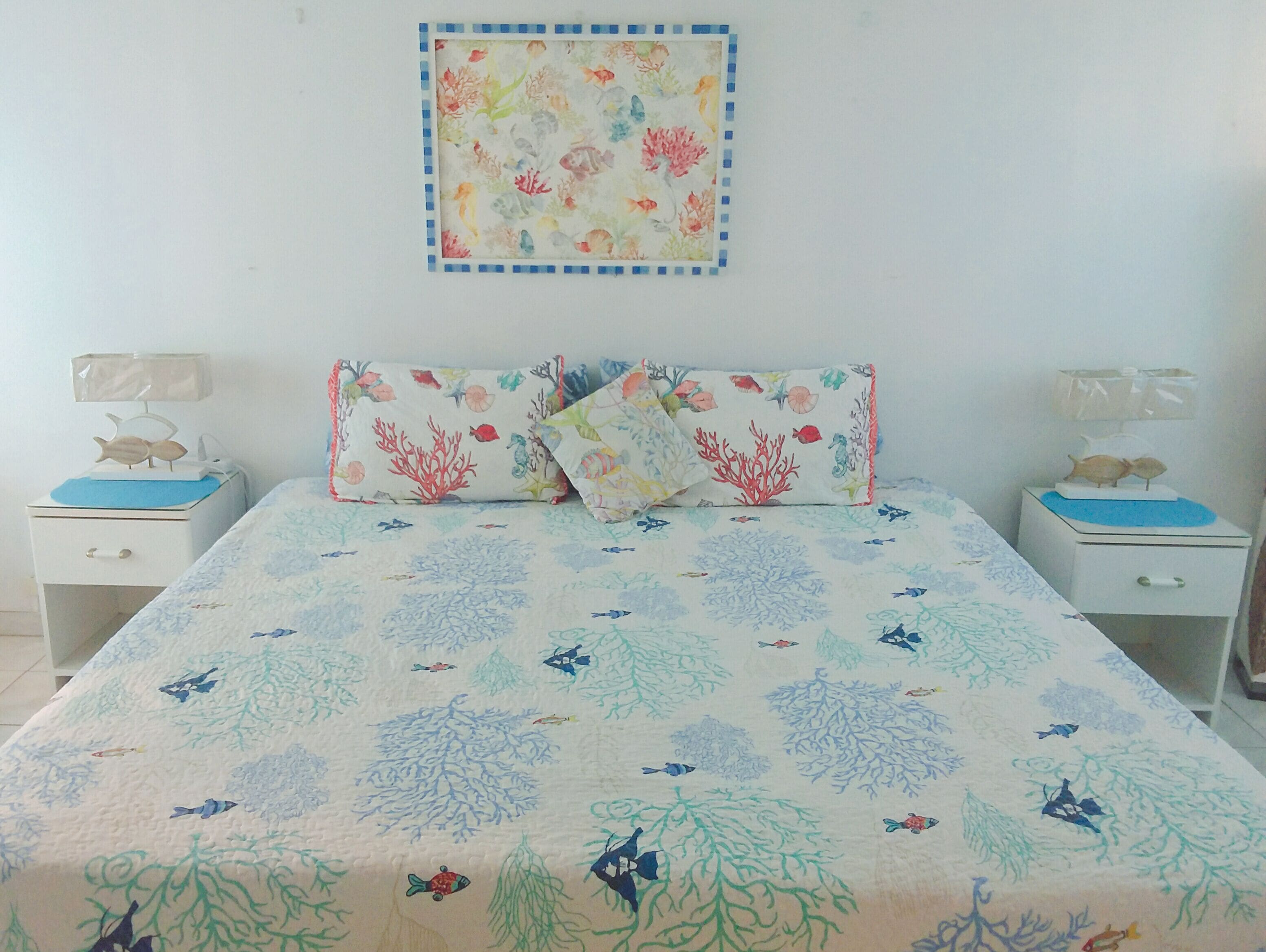 Un dormitorio con una cama, dos mesitas de noche y un cuadro colgado en la pared.
