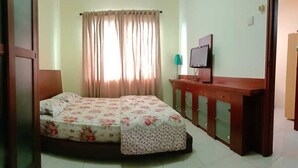 A bedroom with a bed, curtains, a TV, and a wooden desk. - Apartment Sudirman Park 2 Bedrooms & 2 Bathrooms Jakarta (Jakarta)