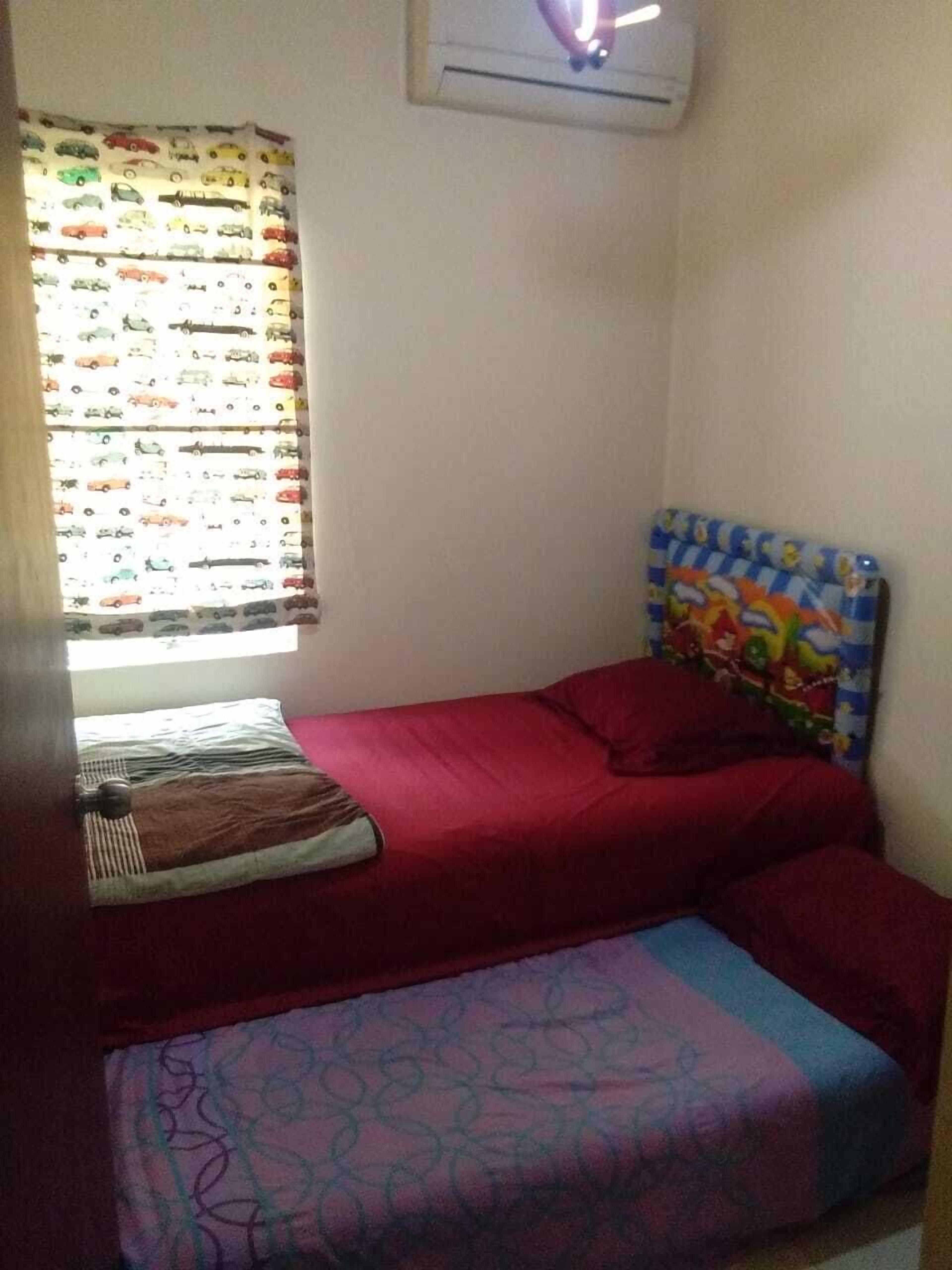 Un dormitorio pequeño con una cama individual, una ventana con cortinas y un aire acondicionado de pared.