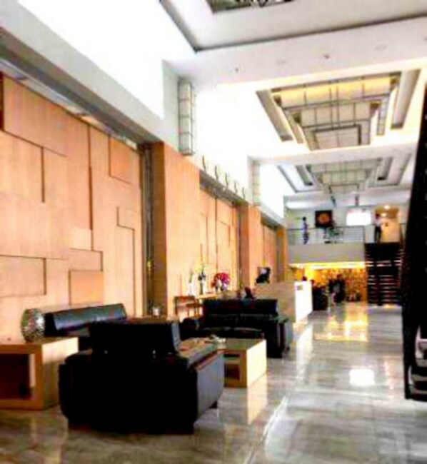 A spacious lobby with a high ceiling, a reception desk, and a seating area with sofas and a coffee table.