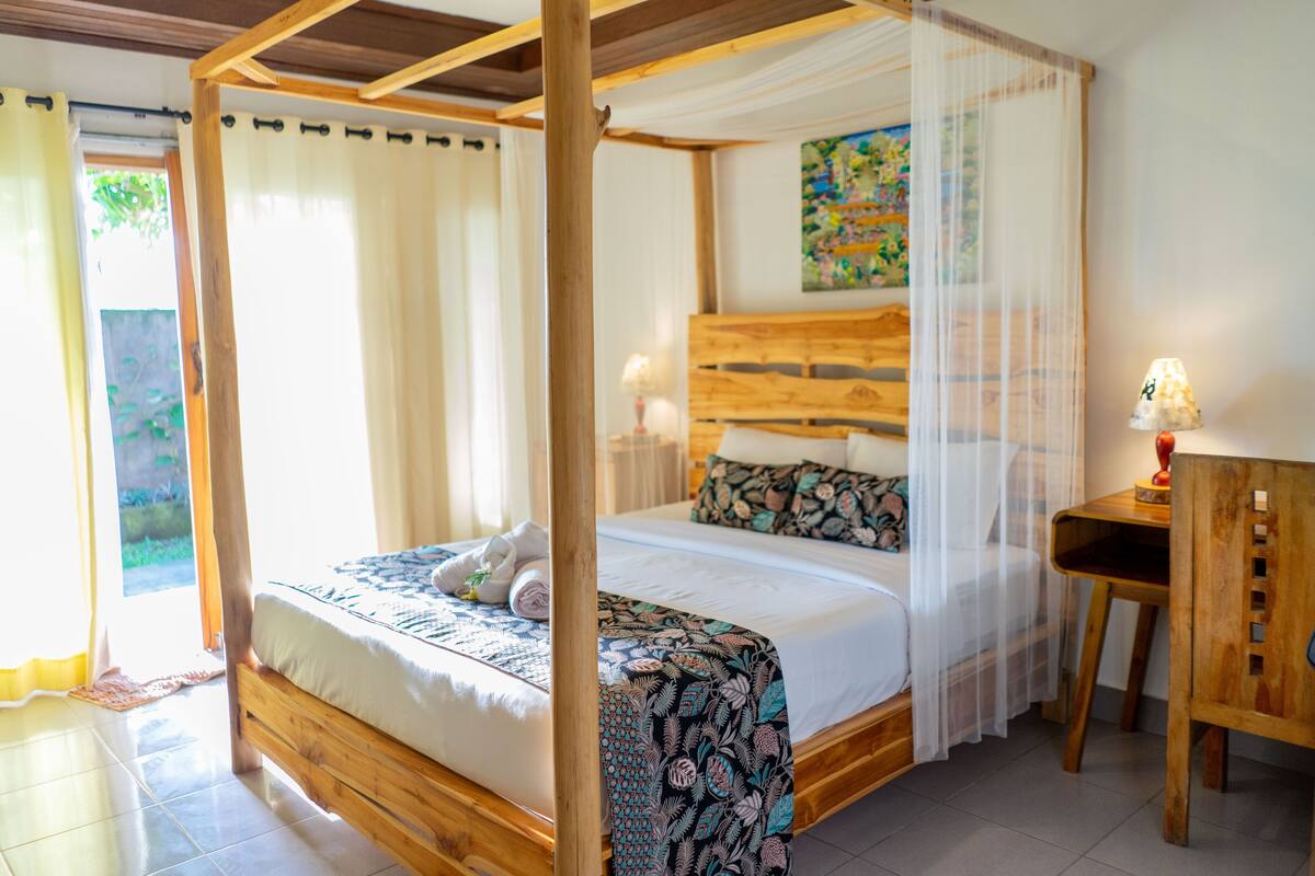 Ein Himmelbett mit Baldachin, einem Holz-Kopfteil und gemusterten Betttextilien.