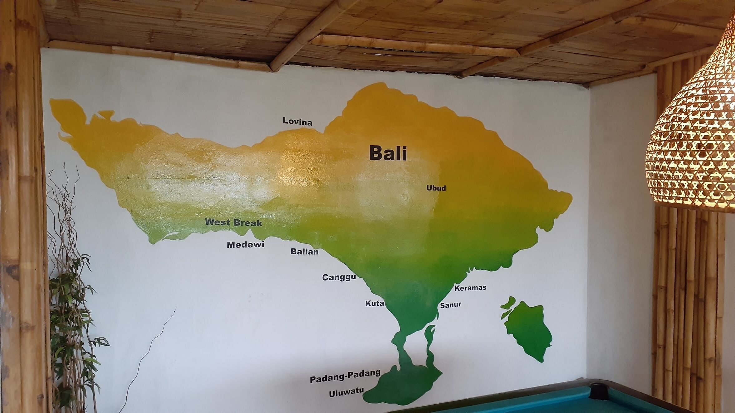 Une carte murale de Bali indiquant différents lieux, notamment Lovina, Ubud et Padang-Padang.